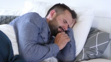 Baş ağrısı, depresif huzursuz adam yatakta yan yatan