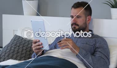 Tablet yatakta yorgun adam tarafından online alışveriş