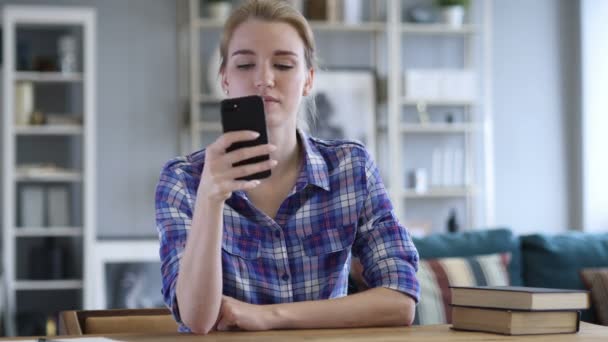 Mujer joven ocupada usando Smartphone mientras se relaja en la silla — Vídeos de Stock