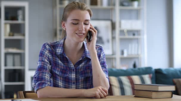 若い女性は椅子でリラックスしながら電話で話しています。 — ストック動画