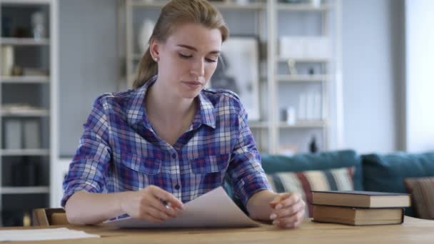 Fundersam ung kvinna skriver på papper, författare arbetar på roman — Stockvideo