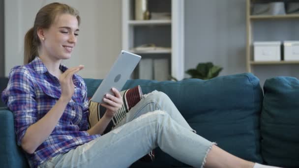 Online czat wideo na tablecie przez kobieta siedzi na kanapie — Wideo stockowe
