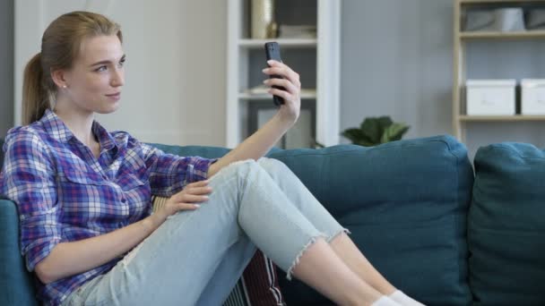 Случайная женщина на диване делает селфи на смартфоне — стоковое видео