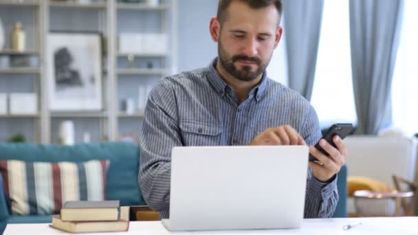 Человек с помощью смартфона и ноутбука на работе — стоковое видео