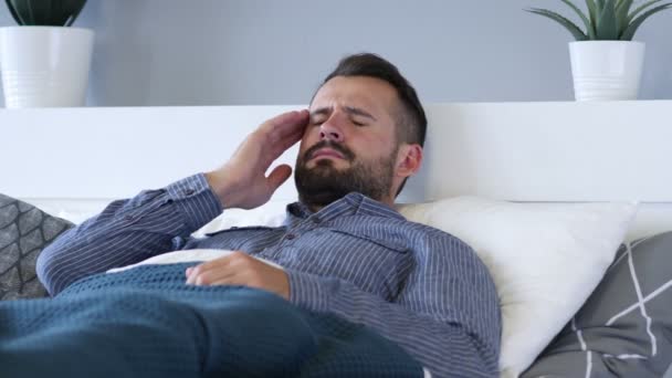 Αναστατωμένος Young Man with πονοκέφαλο ενώ ξαπλωμένος στο κρεβάτι — Αρχείο Βίντεο