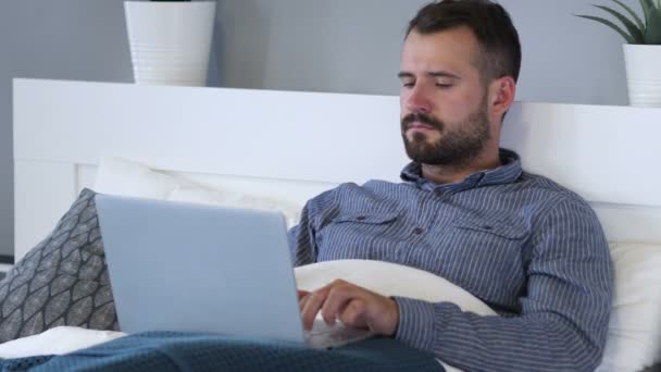 Dor de cabeça, jovem tenso trabalhando no laptop na cama — Vídeo de Stock