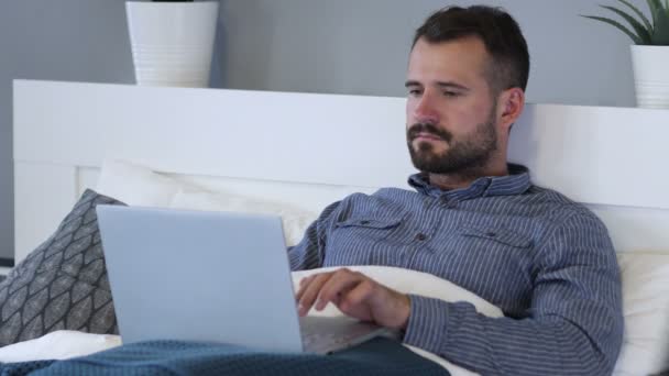 Αντίδραση της επιτυχίας από ευτυχισμένος άνθρωπος που χρησιμοποιούν φορητό υπολογιστή στο κρεβάτι — Αρχείο Βίντεο