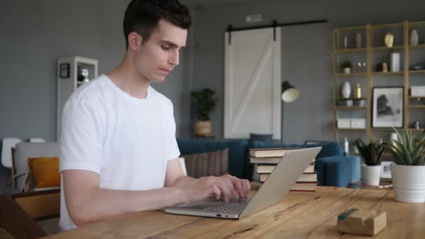 Захоплений чоловік святкує успіх, працює на ноутбуці — стокове відео