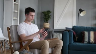 Adam kısa kanepede oturan Smartphone cep telefonu ile mesaj