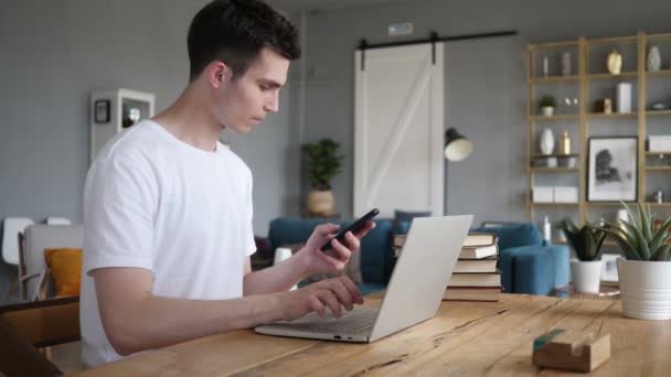 Людина використовує телефон і ноутбук для роботи — стокове відео