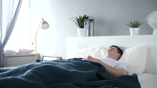 Молодой человек, спящий в постели — стоковое видео