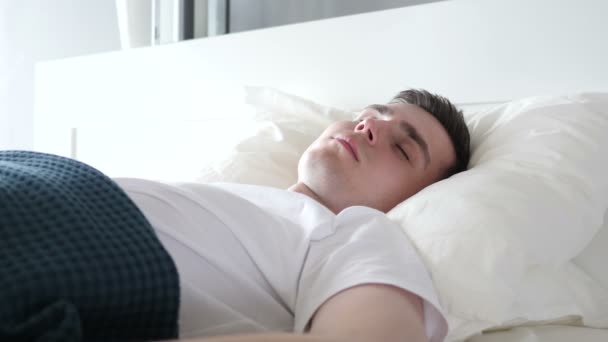 Человек просыпается от сна в постели — стоковое видео