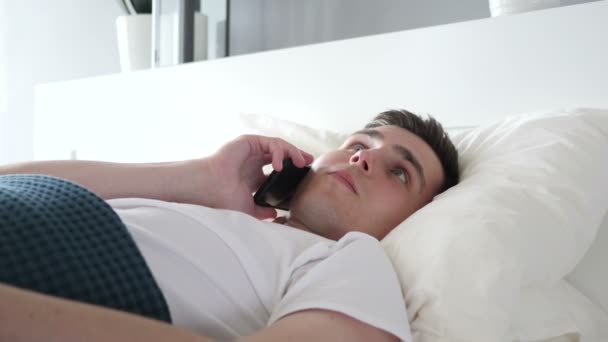 Gros plan de l'homme parlant au téléphone alors qu'il était allongé au lit — Video