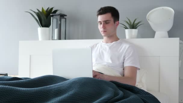 Mann arbeitet am Laptop, während er sich im Bett entspannt — Stockvideo