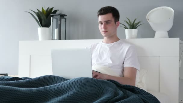 Uomo scioccato chiedendo e lavorando su computer portatile a letto — Video Stock