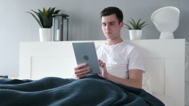 Потеря расстроенный человек с помощью планшета в постели — стоковое видео