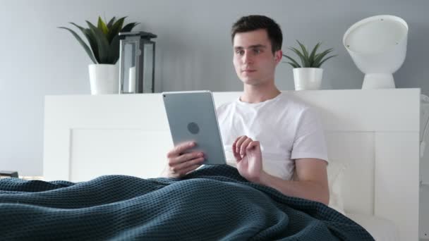 Chat de vídeo on-line em Tablet por homem na cama — Vídeo de Stock