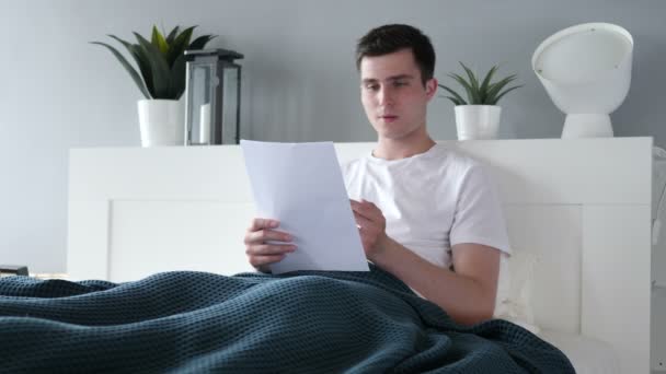 Mann nach Lesen von Dokumenten im Bett aufgeregt — Stockvideo