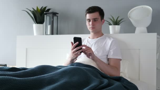 Man använder Smartphone medan liggande i sängen — Stockvideo