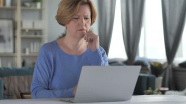 Düşünme ve dizüstü bilgisayarda çalışan dalgın yaşlı kadın kıdemli