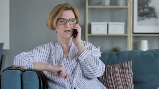 Senior Kvinna pratar telefon, sittande på soffan i sovrummet — Stockvideo