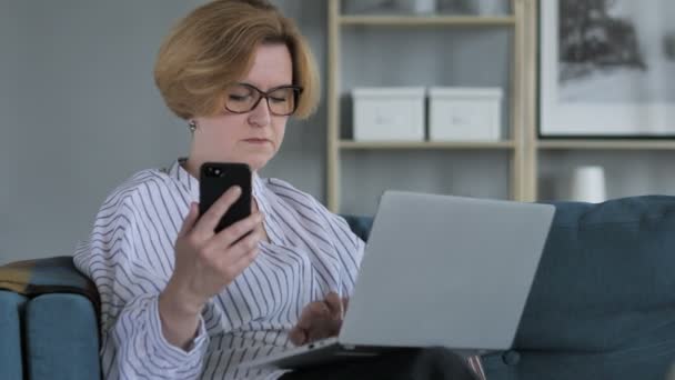 Mulher idosa usando telefone e laptop para o trabalho — Vídeo de Stock