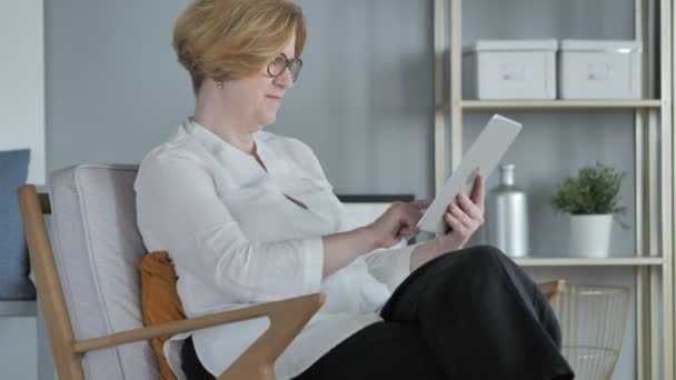 Senior Kvinna beter Internet på TabletPC, sitter på soffan — Stockvideo
