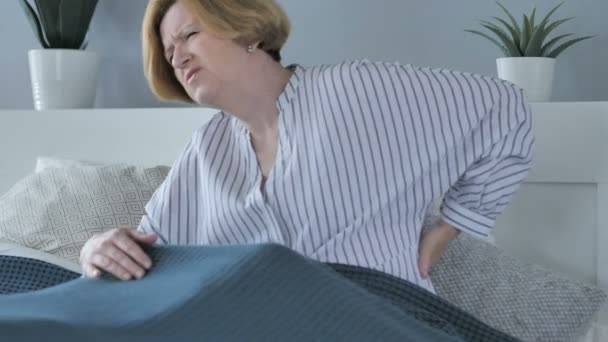 Стара старша жінка з болем спини сидить у ліжку — стокове відео