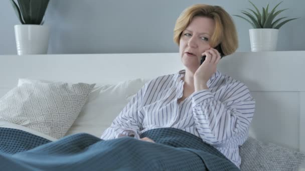 Vecchia donna anziana che parla al telefono mentre si trova a letto — Video Stock