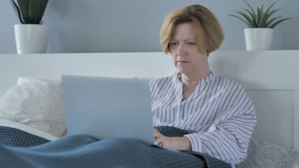 Reação do sucesso pela mulher sênior feliz usando laptop na cama — Vídeo de Stock