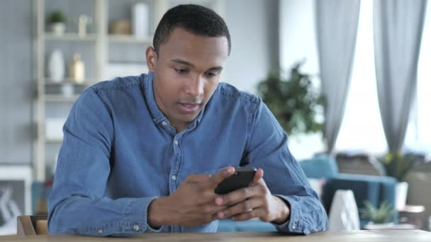 Fiatal afrikai ember izgatott a siker mellett használ Smartphone — Stock videók