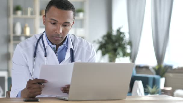 Афроамериканский врач, читающий медицинское заключение, диагностирующий пациента — стоковое видео