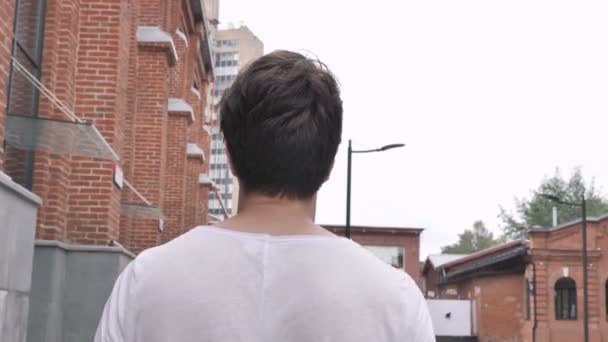 路上を歩くカジュアルな男の背面図 — ストック動画