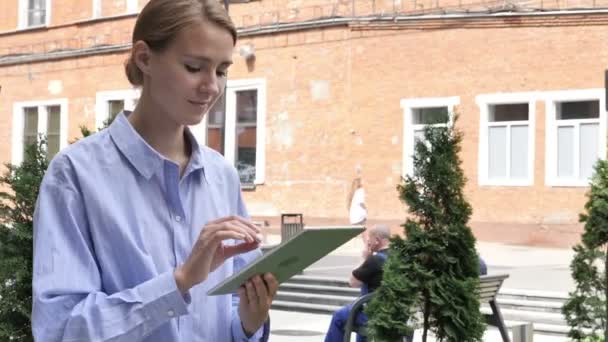 Жінка переглядає планшет під час ходьби на вулиці — стокове відео