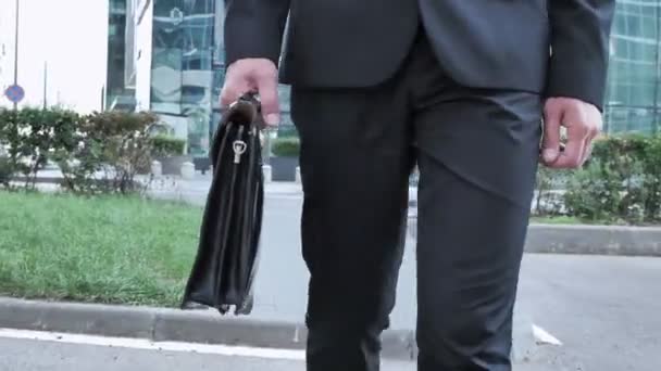 ハンドバッグを手に保持しているビジネスマンの足を歩いてください — ストック動画