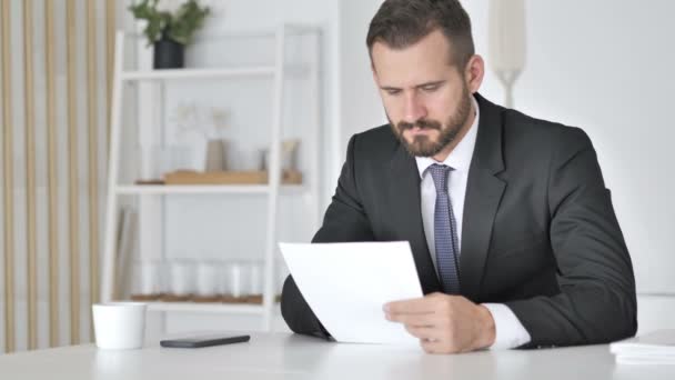 Zakenman viert succes tijdens het lezen van documenten in Office — Stockvideo