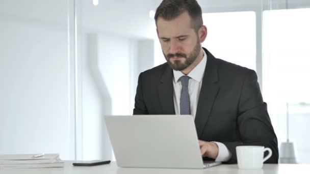 Empresario saliendo de la oficina después de cerrar el ordenador portátil en el trabajo — Vídeos de Stock