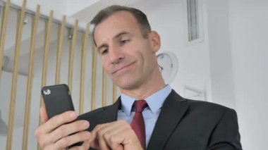 Online finansal ticaret için Smartphone kullanarak işadamı orta yaşlı