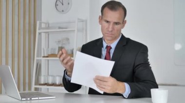 Orta yaşlı işadamı sonuçları tarafından hayretler içinde merak