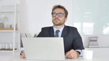 Düşünme ve ofiste oturan işadamı gülümseyen