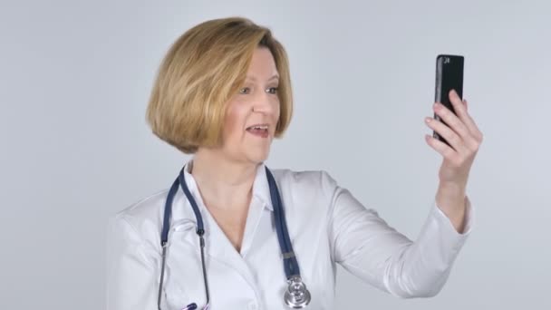 白背景の古い医者によってスマート フォンでビデオ チャット — ストック動画