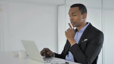 Düşünme ve dizüstü bilgisayarda çalışan dalgın rahat Afro-Amerikan işadamı
