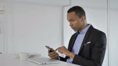 Smartphone kullanarak, ileti yazmakta rahat Afro-Amerikan iş adamı