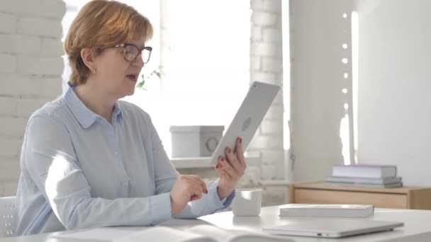 職場で古い女性によってタブレットを介してオンライン ビデオ チャット — ストック動画