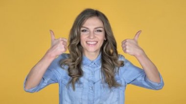 Genç kız el başparmak yukarıya sarı arka plan izole