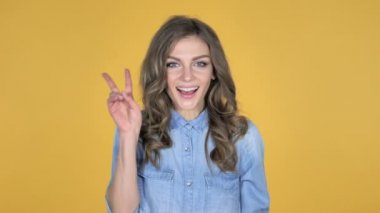 Genç kız üzerinde sarı arka plan izole zafer işareti