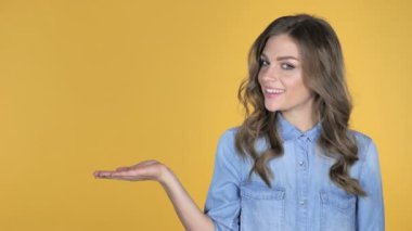 Genç kız gösteren ürün yanında, sarı arka plan