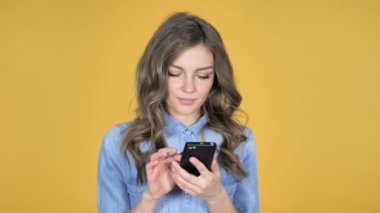 Genç kız heyecanlı başarı kullanarak Smartphone izole sarı arka plan üzerinde süre için