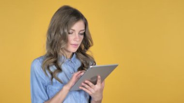 Genç kız heyecanlı başarı kullanarak Tablet izole sarı arka plan üzerinde süre için