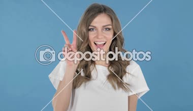 Genç kız üzerinde mavi arka plan izole zafer işareti